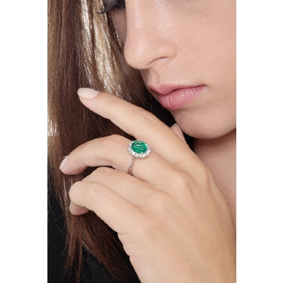 Halo ring with oval cut central emerald and diamonds in white gold 18k