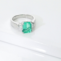 18k white gold ring with a central emerald and side diamonds 