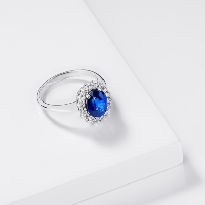 Anello contorno in oro bianco 18k con zaffiro ovale blu e diamanti