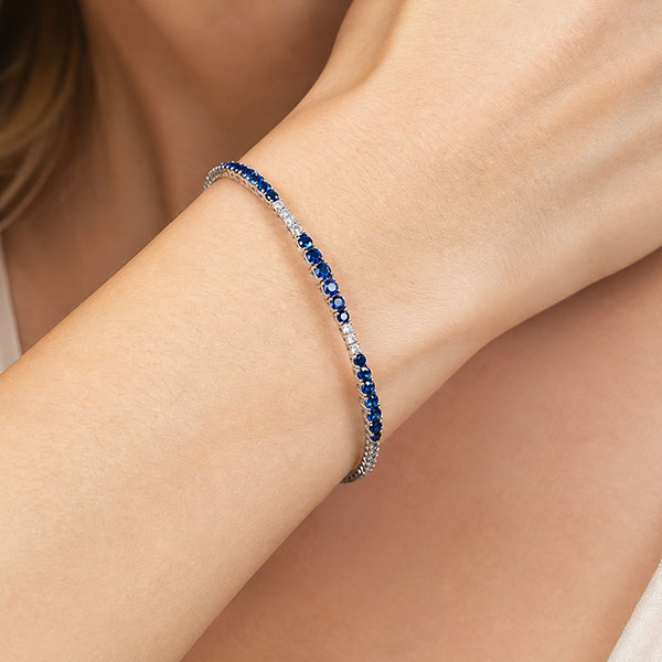 Bracciale tennis in oro bianco con zaffiri blu e diamanti, indossato al polso di una donna